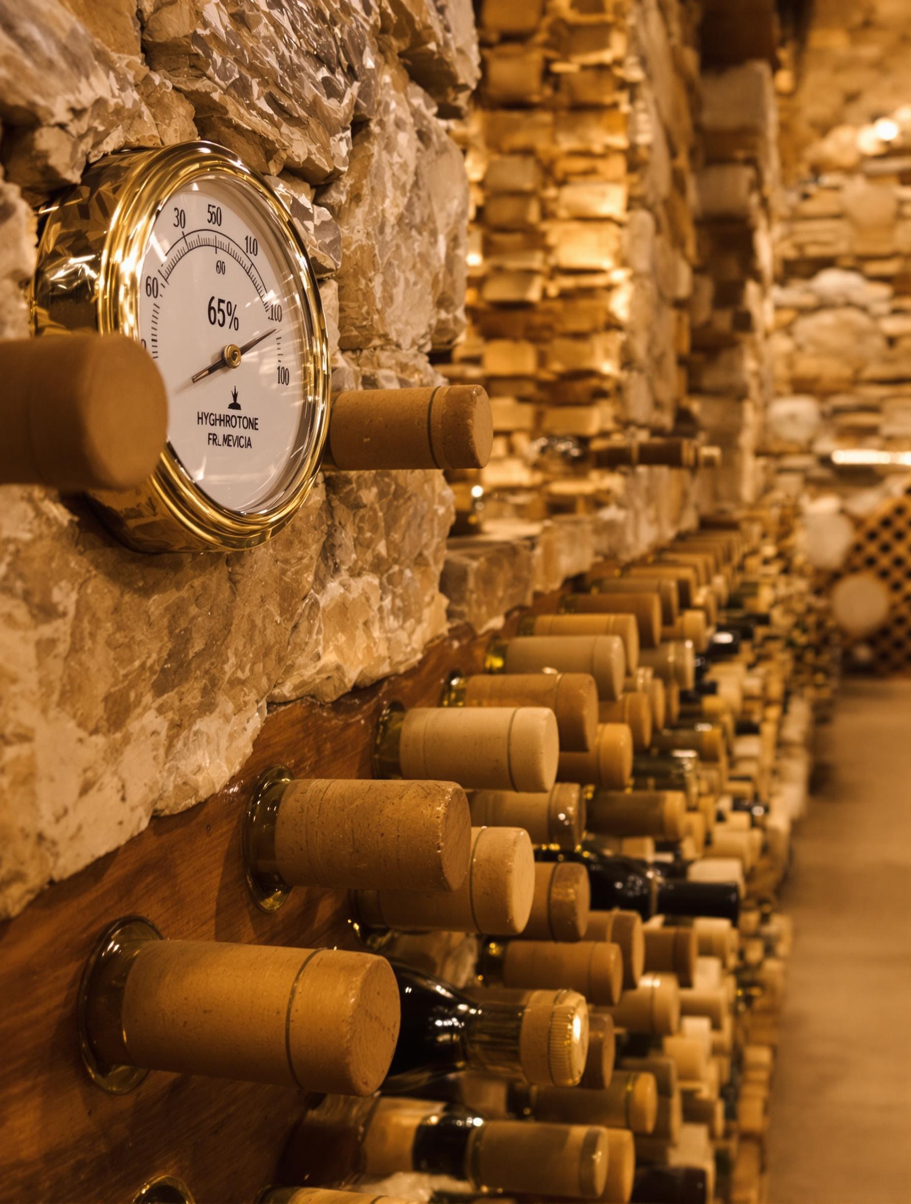 Cave à vin traditionnelle avec hygromètre affichant 65 %, bouchons bien conservés.