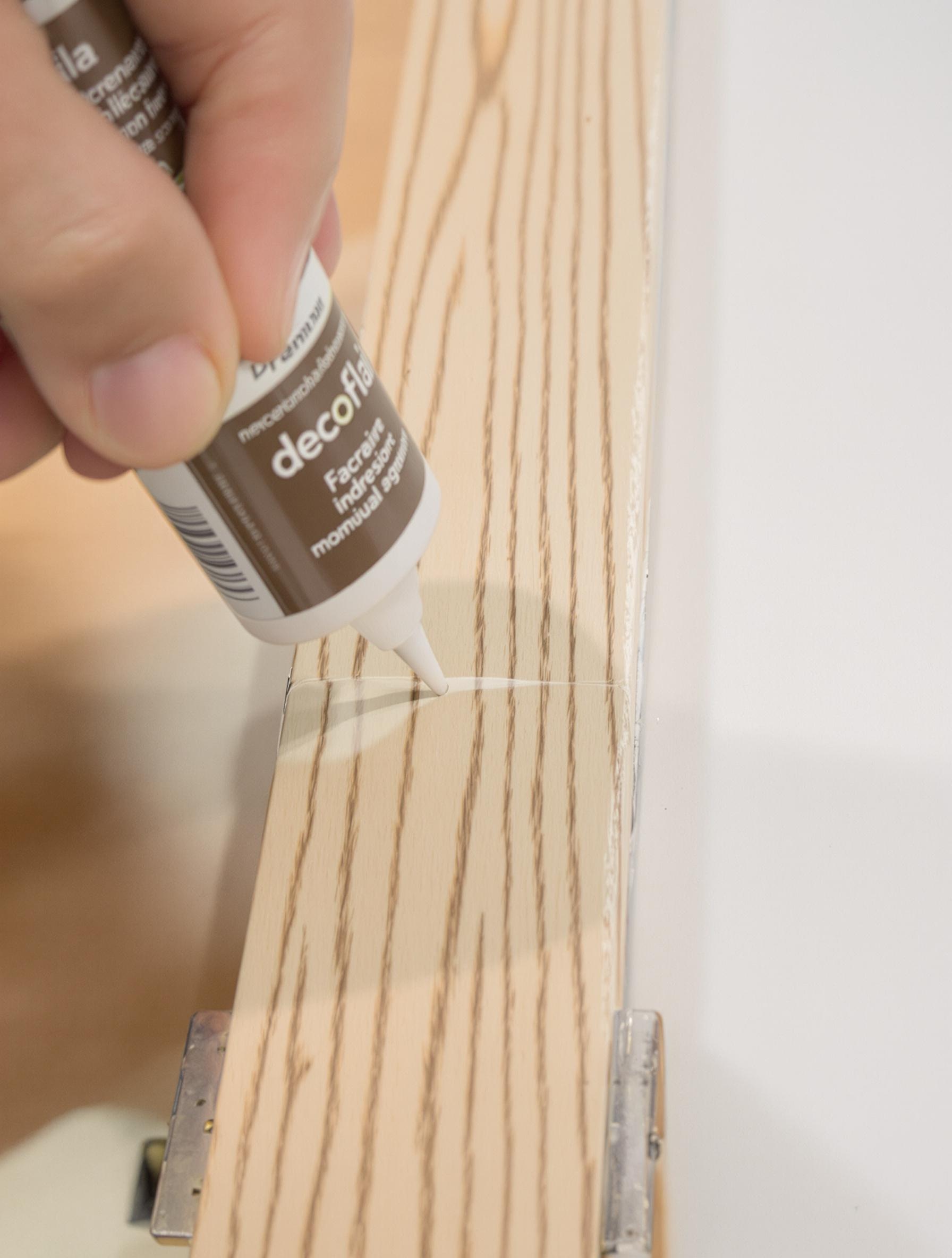 Application précise de colle décoflair sur une plinthe en bois sans débordement.