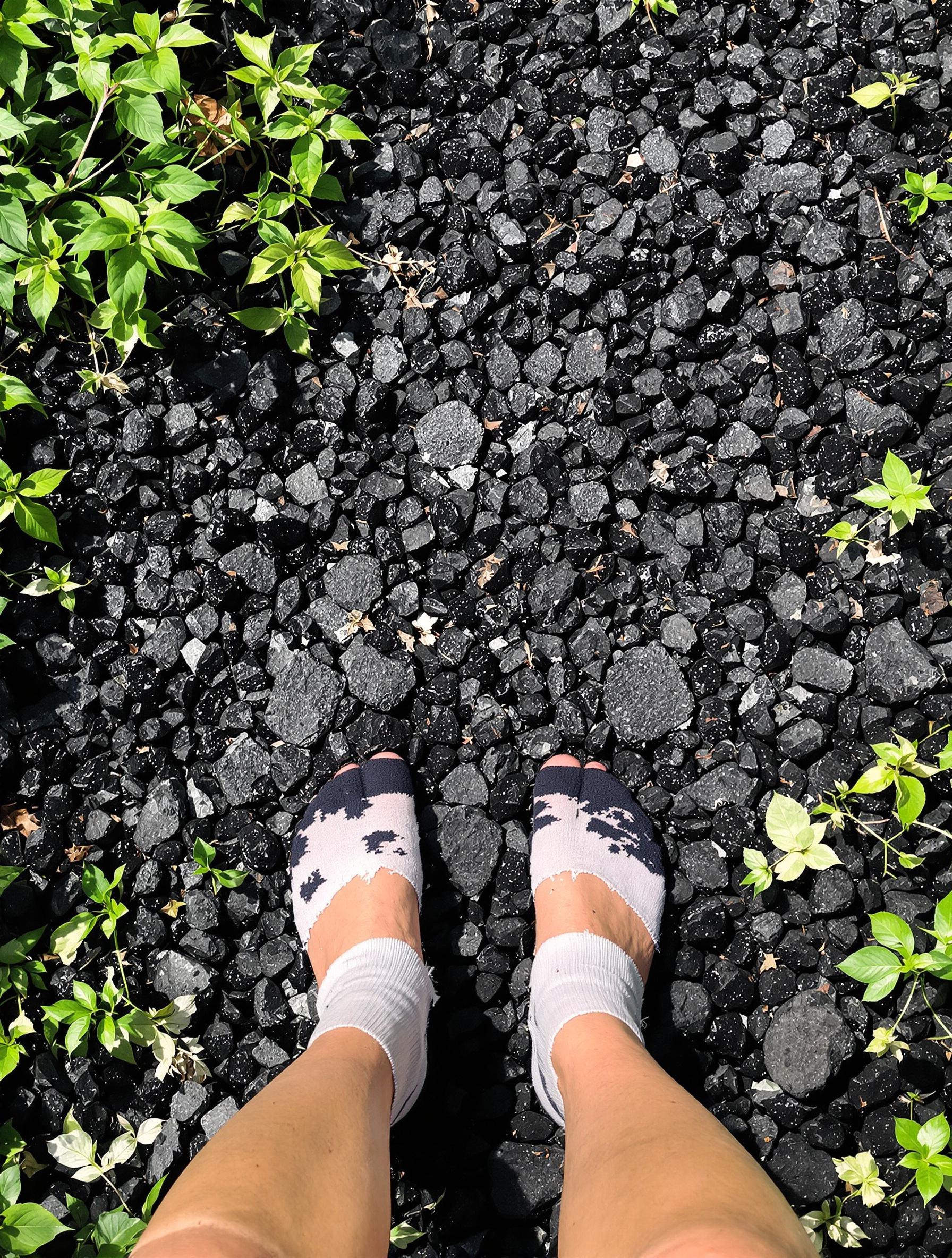 Inconfort des pieds nus sur pouzzolane dans un jardin bohème