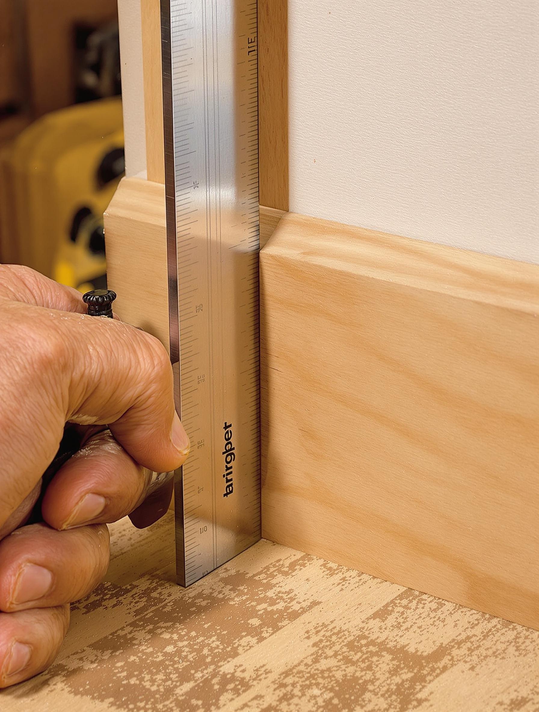 Vérification de l’ajustement des plinthes avec une équerre dans un atelier.