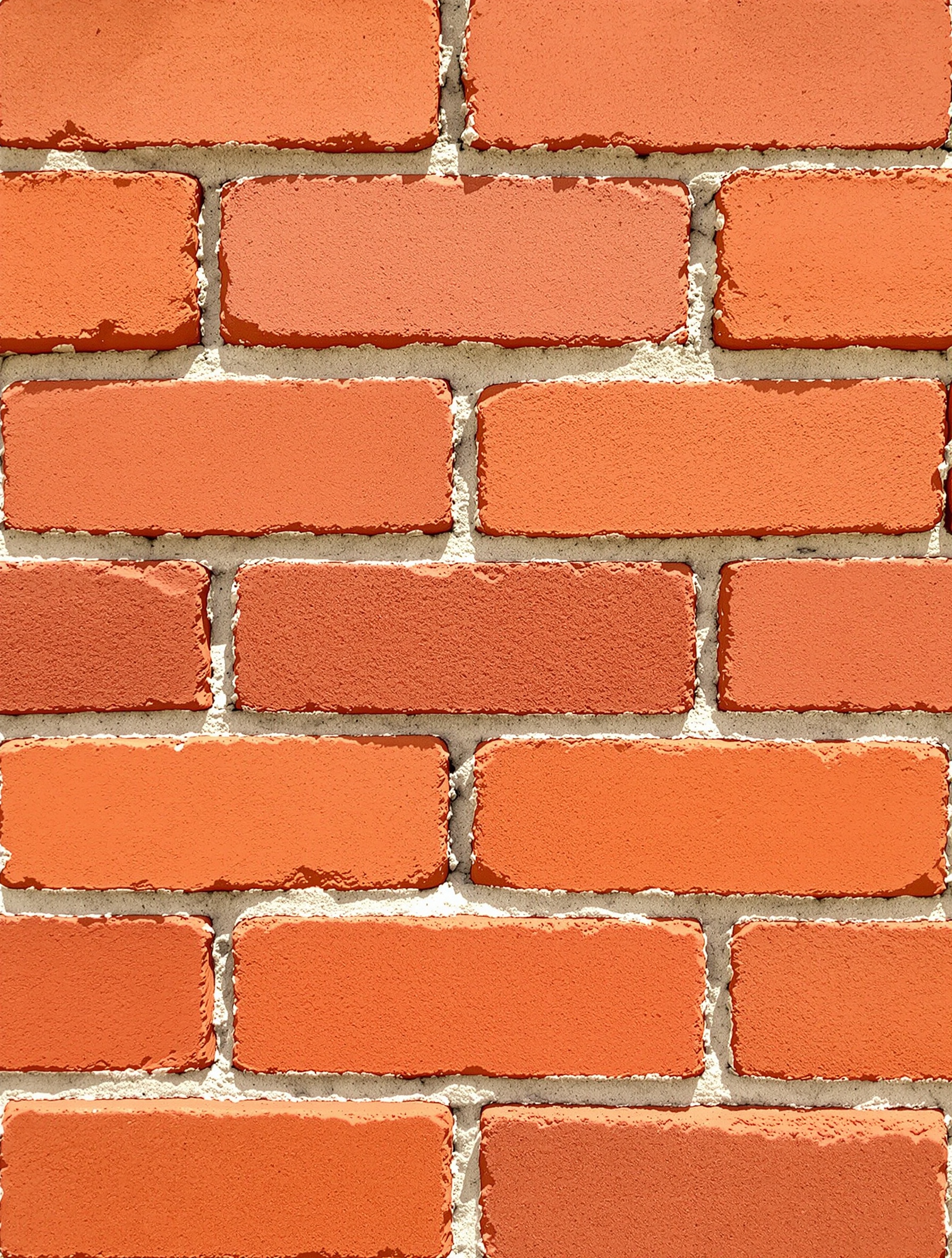 Un mur extérieur en briques apparentes, montrant la richesse des teintes de terre cuite et la texture régulière des briques, évoquant la chaleur et l'authenticité.