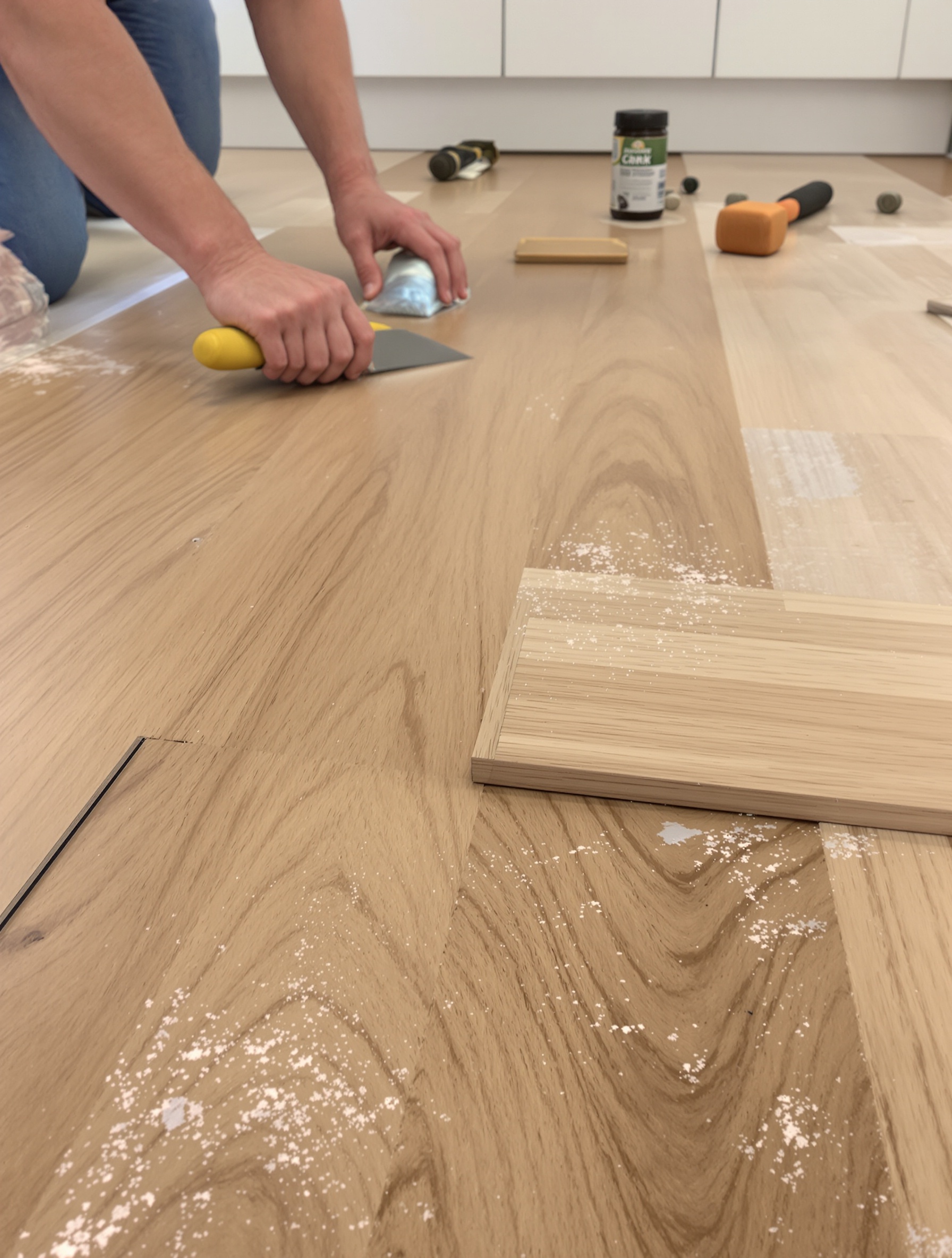 Plan rapproché sur pose collée d'un parquet massif dans une cuisine