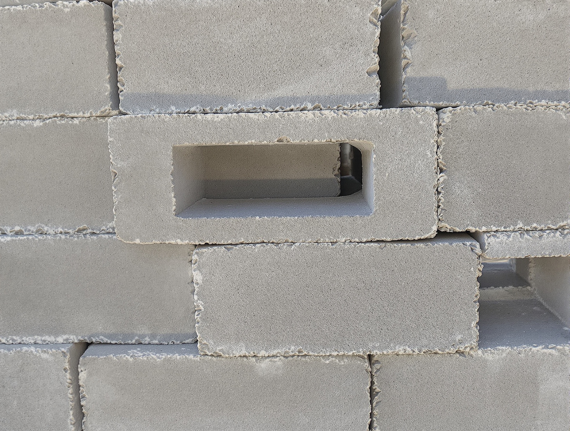 Un tas de parpaings bruts prêts à l'emploi, montrant leur texture poreuse et leur forme rectangulaire standard, symbolisant la simplicité et la robustesse du matériau.