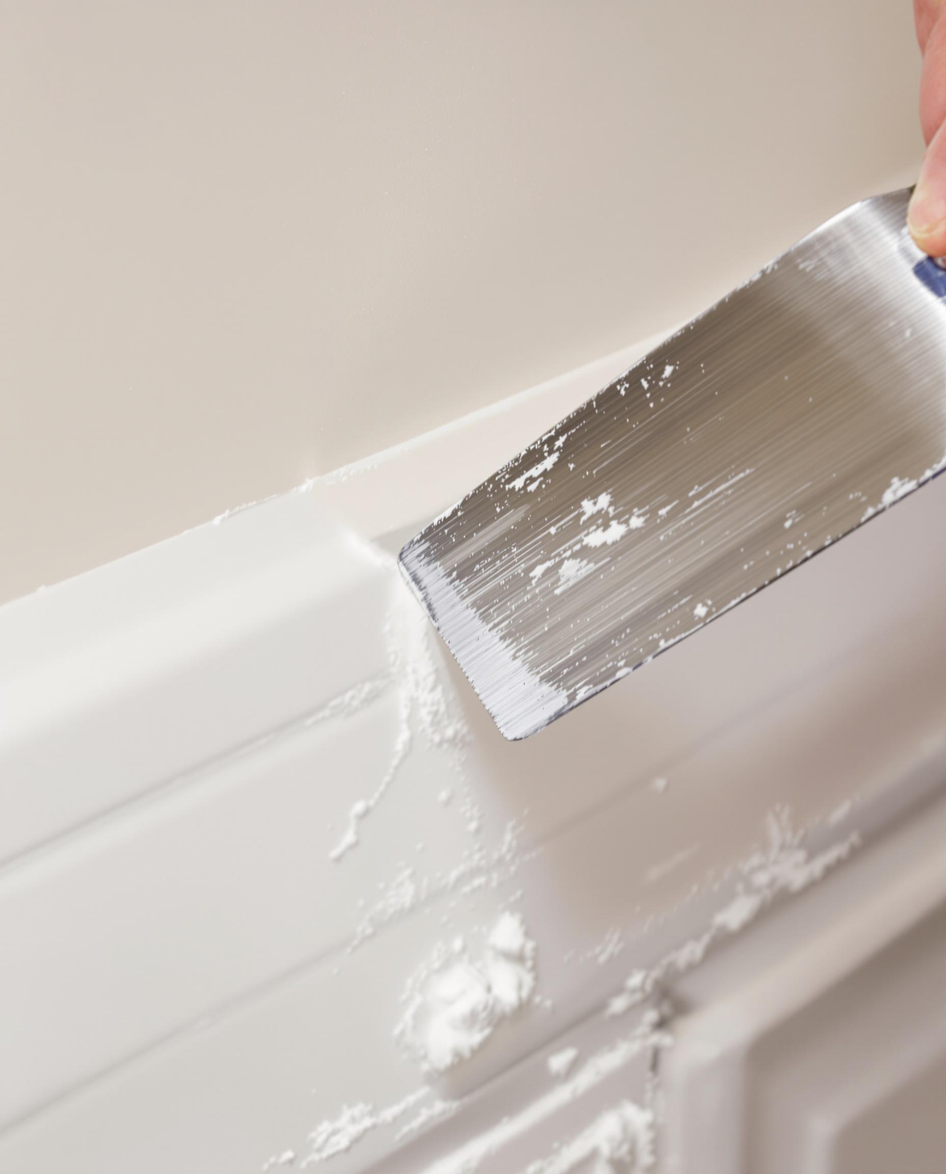 Application de mastic sur un angle sortant avec une spatule pour une finition propre.
